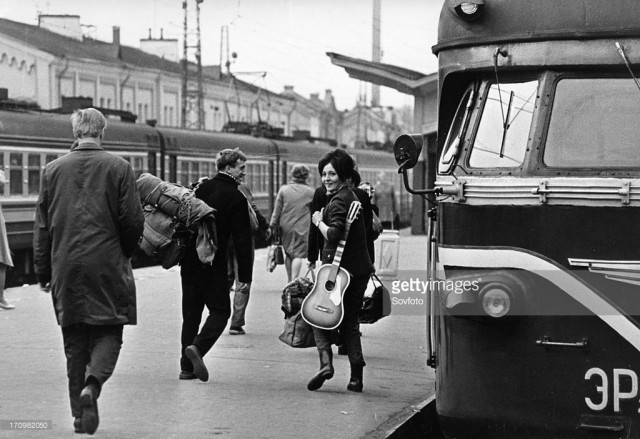 A young Russian couple at a Moscow train station, leaving the city with rucksack and guitar, vacation, USSR (January 02, 1970).jpg