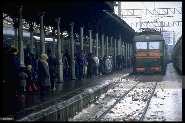 Platform-bound passengers, laden w. shopping & overnight-sized bags waiting as train pulls into Belorussian train station (February 19, 1992).jpg