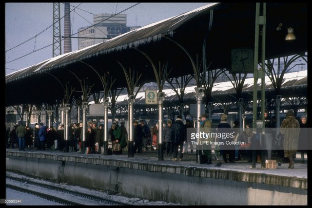 Passengers carrying shopping & overnight-sized bags poised on platform, waiting for commuter train (Elektrichka) to Rieutovo suburb, at Kursky railway station in Moscow (February 19, 1992).jpg
