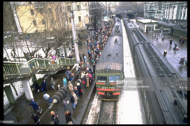 Rail passengers carrying shopping & overnight-sized bags packing platform, waiting to bd. train, at Belorussky railway station, Moscow (February 19, 1992).jpg